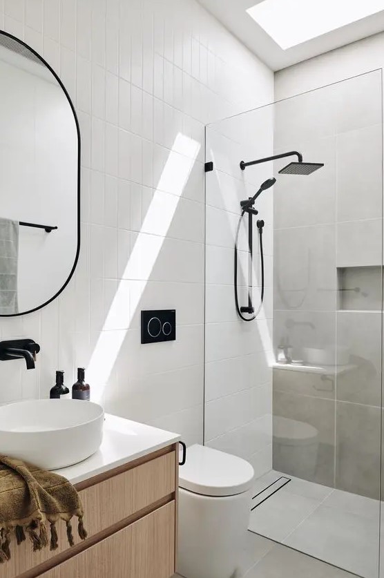 a small contemporary bathroom clad with grey concrete and white skinny tiles, with a stained vanity and black fixtures