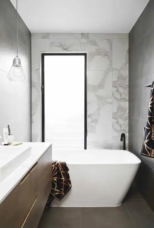 a small contemporary bathroom with a tub, a frosted glass window, a floating vanity and a square sink, pendant lamps
