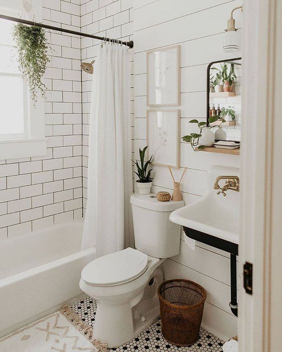 a small farmhouse bathroom with shiplap and white subway tiles, a tub, a wall-mounted sink, some decor and potted greenery