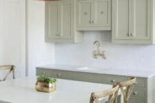 a small sage green kitchen with shaker and flat panel cabinets, a white subway tile backsplash and white countertops plus a catchy brushed lamp