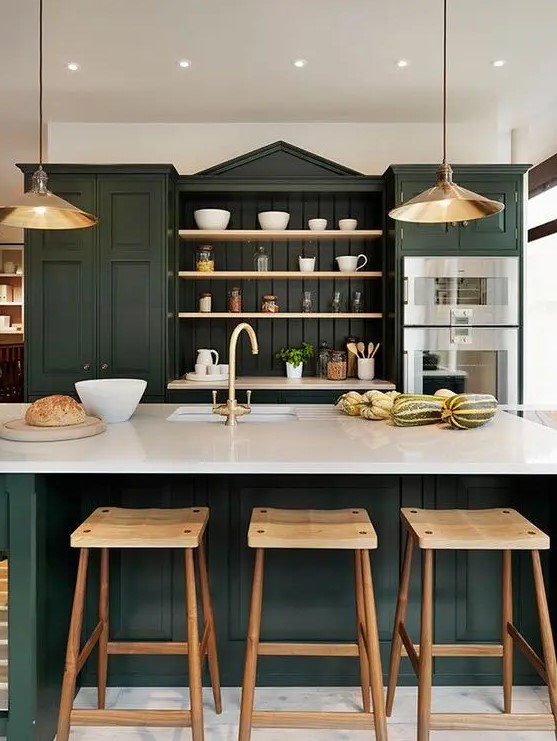 a sophisticated hunter green kitchen with vintage cabinets, open shelves, white countertops, metal pendant lamps and wooden stools