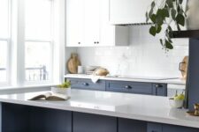 a sophisticated kitchen with upper white cabinets and lower navy ones, a white tile backsplash and white countertops