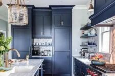 a statement blue kitchen with a marble tile backsplash, stone countertops and catchy pendant lamps and sconces