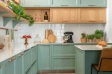 a stylish mint kitchen with shaker cabinets and a row of stained ones, a white tile backsplash and a kitchen island with stools