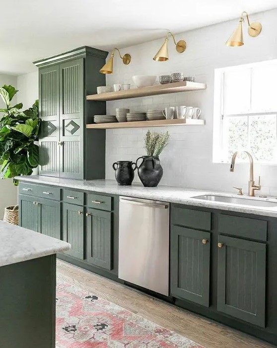 a stylish olive green farmhouse kitchen with fluted cabinets, white stone countertops, open shelves, brass and gold lamps