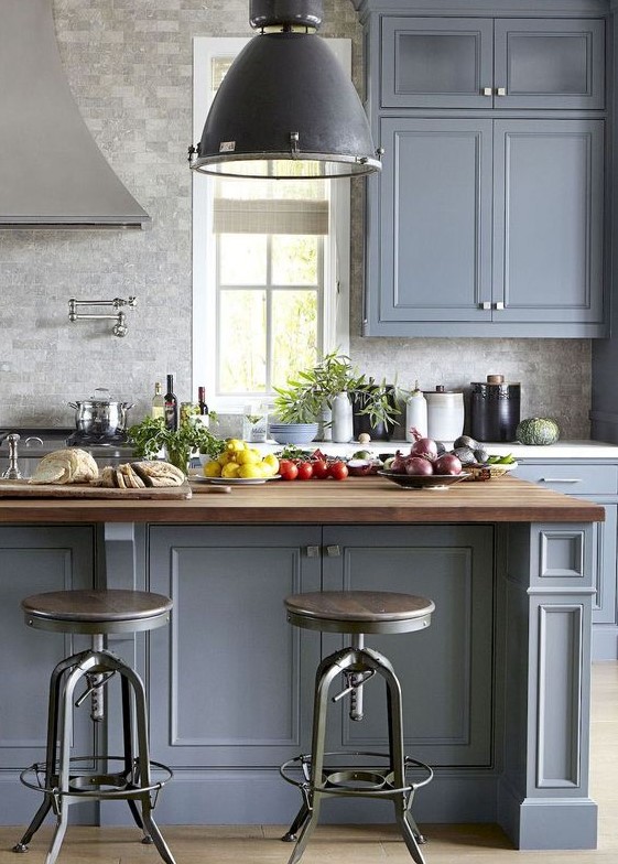 a traditional kitchen in slate blue with a grey tile, butcherblock countertops and vintage furniture and lamps