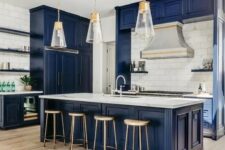 a vintage-inspired bold blue kitchen with a white tile backsplash, white stone countertops, pendant lamps and wooden stools