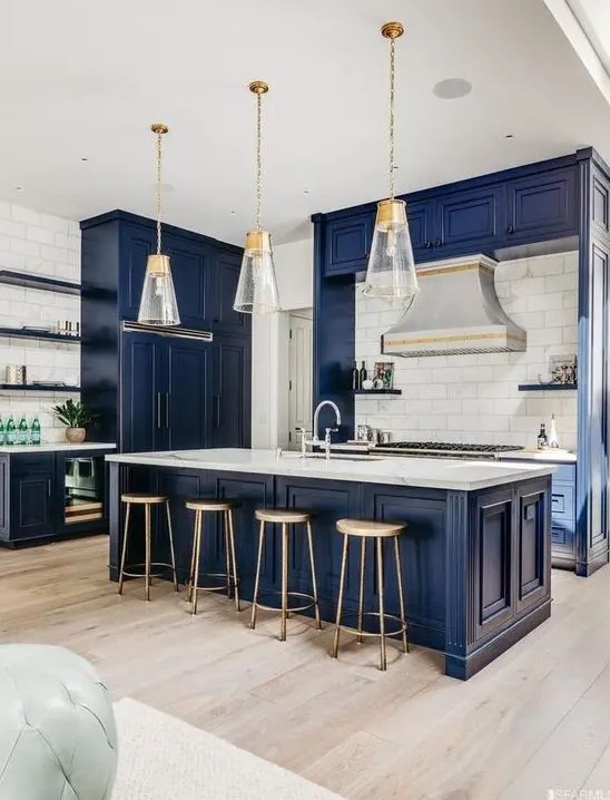 a vintage-inspired bold blue kitchen with a white tile backsplash, white stone countertops, pendant lamps and wooden stools