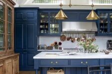 a vintage-inspired kitchen in classic blue, with a white marble backsplash and countertos plus gold lamps
