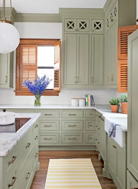 a vintage sage green kitchen with shaker cabinets, a white subway tile backsplash and stone countertops and brass handles
