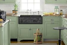 a welcoming sage green vintage kitchen with a white tile backsplash, grey stone countertops and a dark sink is wow