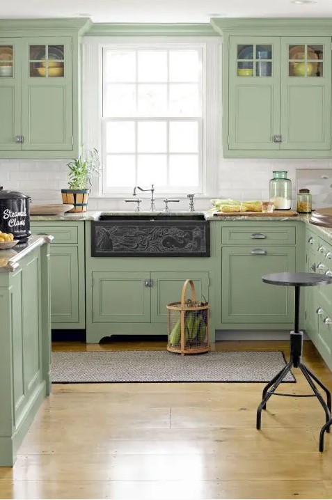 a welcoming sage green vintage kitchen with a white tile backsplash, grey stone countertops and a dark sink is wow