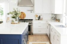 a white farmhouse kitchen with shaker cabinets, a navy kitchen island, a white tile backsplash and pendant lamps