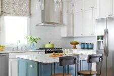 a white kitchen with a grey tile backsplash and a blue kitchen island plus white stone countertops is chic
