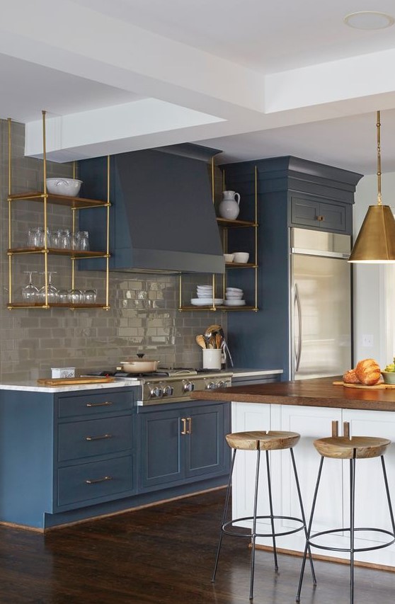 an elegant vintage blue kitchen with a grey subway tile backsplash and touches of gold and natural wood here and there