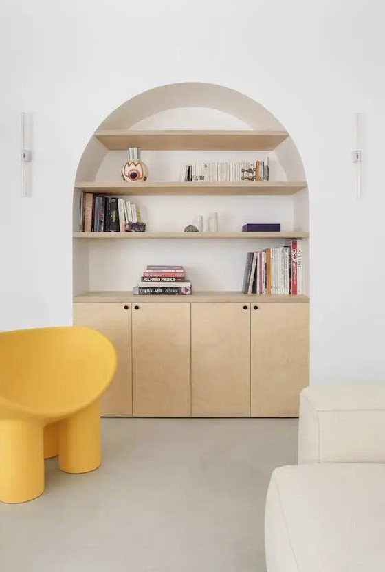 an arched niche with light-stained shelves with books and decor and a built-in cabinet for storage is a lovely idea