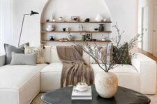10 a beautiful minimalist living room in neutrals, with an arched niche with shelves and chic decor, with a low sofa and a black coffee table