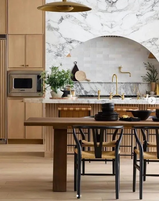 a sophisticated modern farmhouse kitchen with sleek cabinets and a fluted kitchen island, an arched niche with a shelf for decor and a dining zone