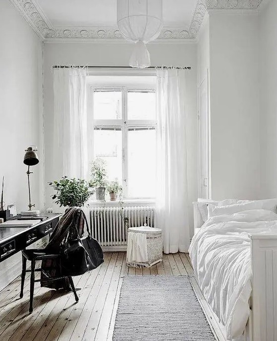 a serene and airy guest bedroom with lots of white and a vintage black desk plus chair to stand out