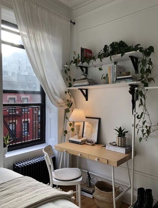 a Scandinavian guest bedroom with open shelves, a lightweight desk, a white chair, a bed and some baskets and potted greenery
