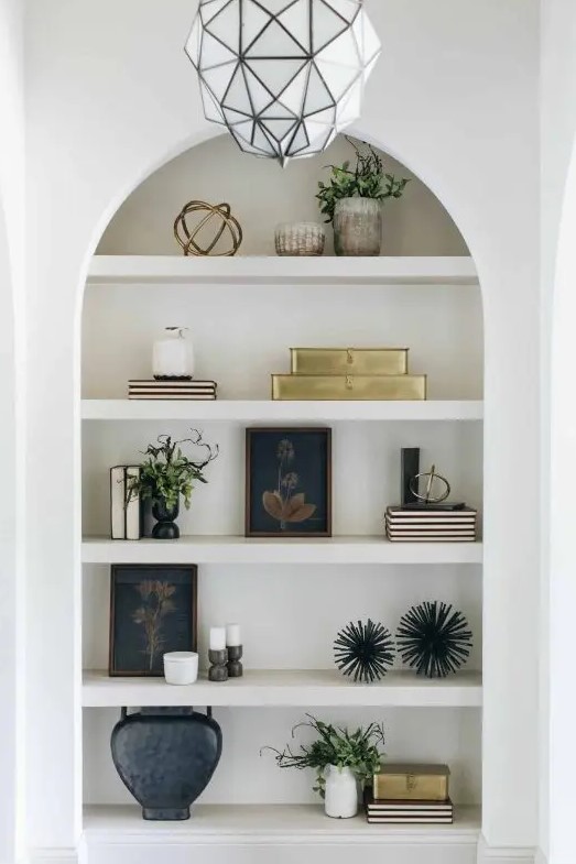 a large arched niche with shelves and lots of stuff on display - books, plants, vases and candles is a cool idea
