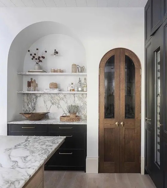 a contemporary kitchen with a large arched niche with built-in dark cabinets, open shelves and a marble backsplash is adorable