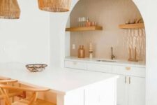 20 a lovely boho kitchen with white cabinets, an arched niche clad with tan tiles, open shelves, gold fixtures, pendant lamps