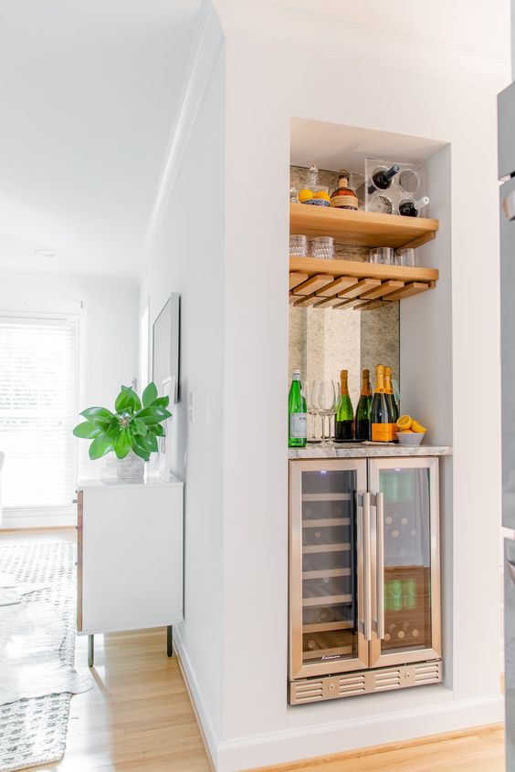 a deep niche with a mirror and shelves and a built-in wine cooler is a lovely idea for a home bar