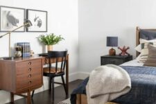 30 a guest bedroom with a bed and nightstands, a wicker chest for storage, a small stained desk and a black chair and some art