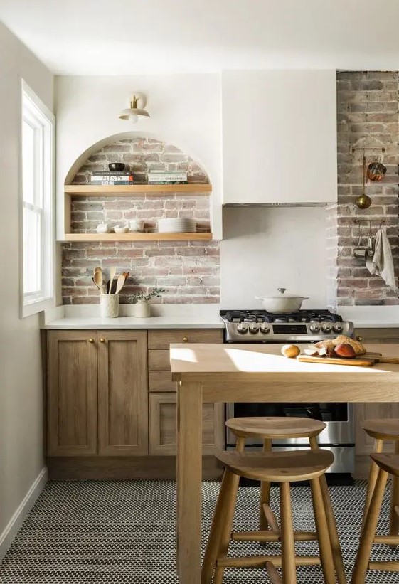 a modern farmhouse kitchen with stained lower cabinets, a brick backsplash, an arched niche with shelves fro storage and display
