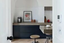 32 a modern kitchen with navy cabinets, grey granite countertops, an arched niche clad with tiles and artwork