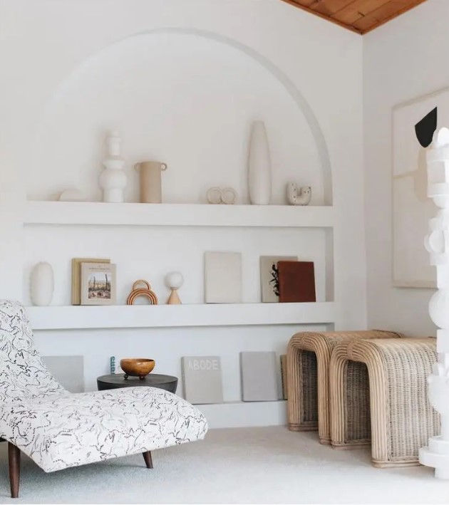 a neutral living room with an arched niche showing off vases and books instead of some furniture