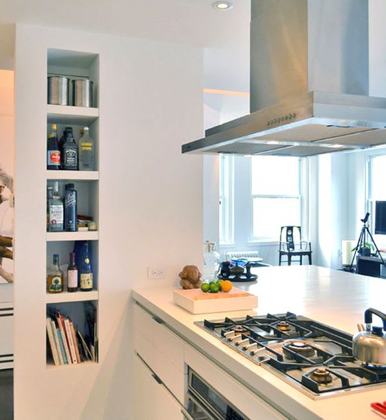 a modern kitchen with niches used for books, wine bottles and oils, these are a very functional solution