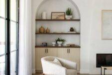 36 a neutral living room with an arched niche with stained shelves and a cabinet, with beautiful decor that adds interest to the space