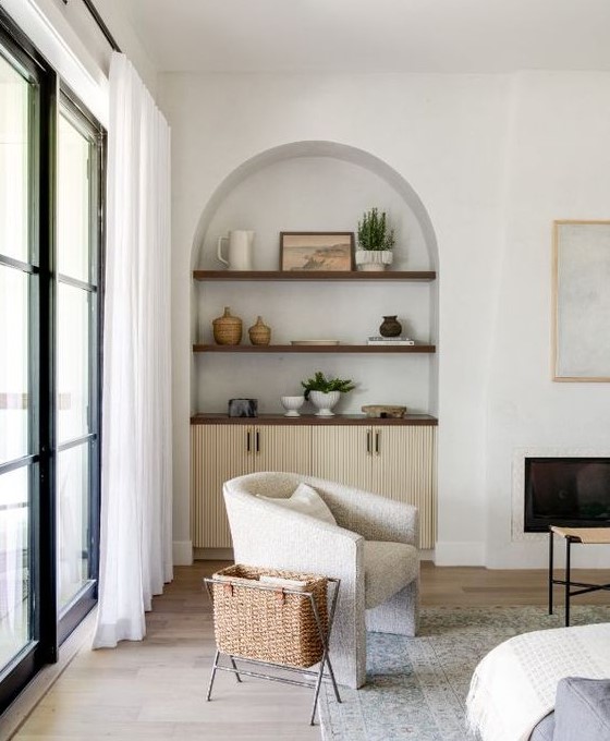 a neutral living room with an arched niche with stained shelves and a cabinet, with beautiful decor that adds interest to the space