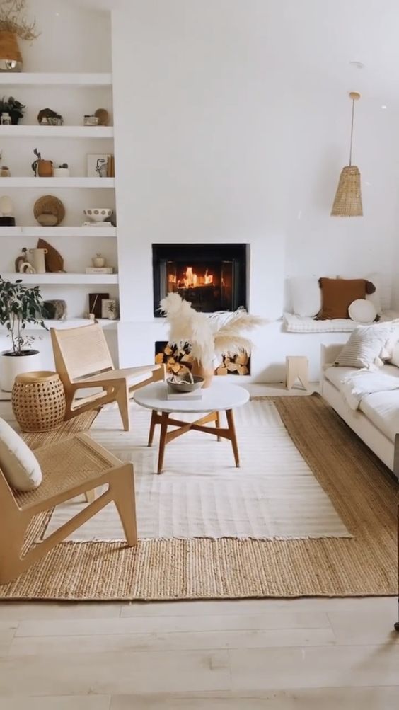 a neutral living room with built-in niche shelves and a seat, with a fireplace, a white sofa and woven chairs