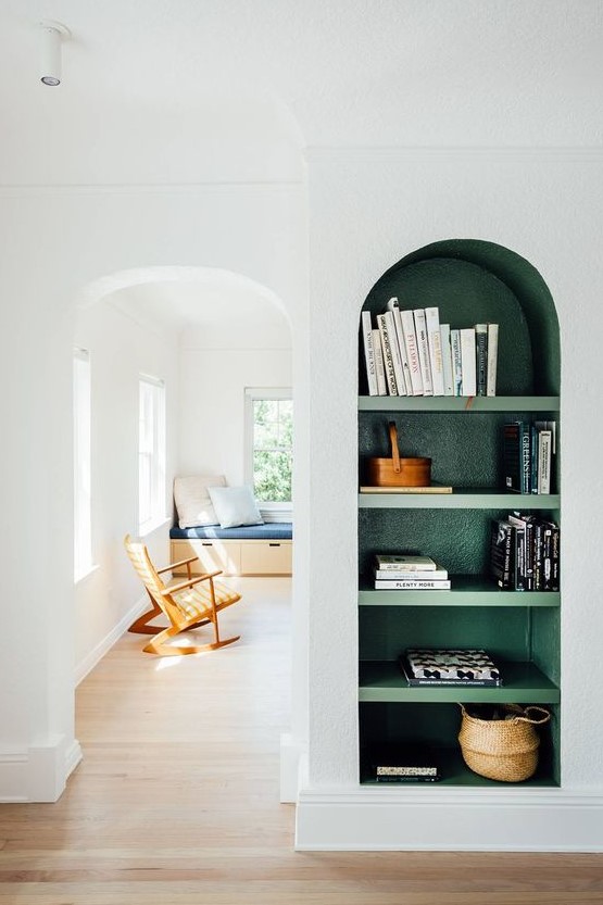 a neutral space with a green arched wall niche with shelves, with books and baskets that is a bold color touch to the space