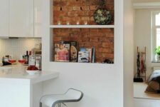 41 a sleek white kitchen with a niche done with red brick used for displaying some decor and potted greenery