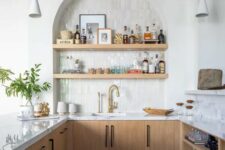 43 a stylish modern kitchen with stained lower cabinets, white stone countertops, an arched niche with open shelves that are used as a home bar