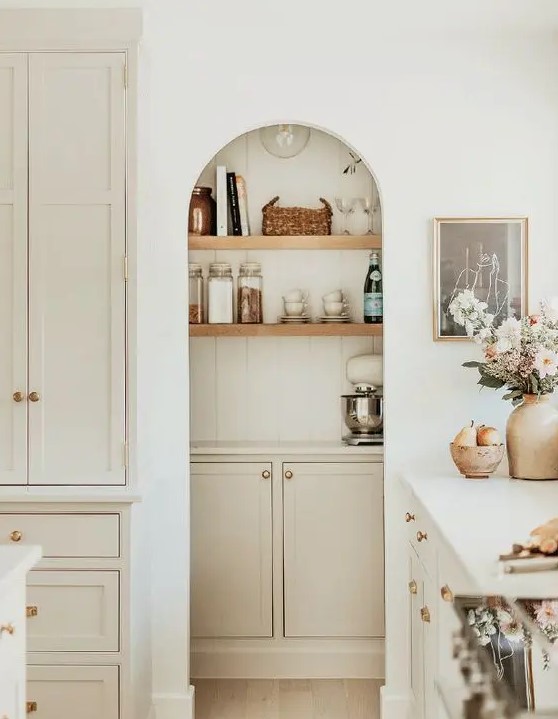 a white modern farmhouse kitchen with an arched niche that houses a pantry with shelves, a cabinet is a lovely idea that saves space