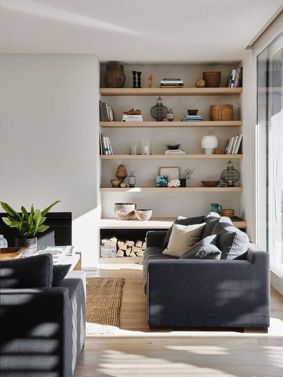 a stylish modern living room with a glazed wall, niche shelves with decor, graphite grey sofas, a fireplace and a coffee table