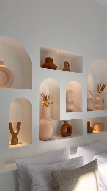 a whole series of arched lit up niches with lovely ceramic vases is a cool and chic idea for a boho living room