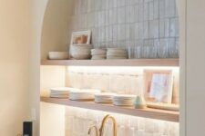 52 an arched niche clad with skinny tiles, open lit up shelves, porcelain and glasses is a decorative and practical idea for a kitchen
