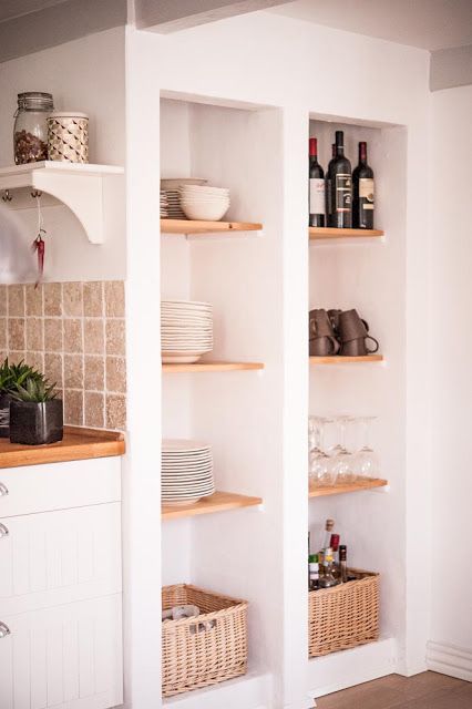 deep niches with wooden shelves and baskets that are used for storing dishes, glasses and plates and wine