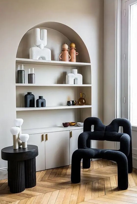 an arched niche with shelves that are used to display beautiful decor and candleholders and built-in cabinets