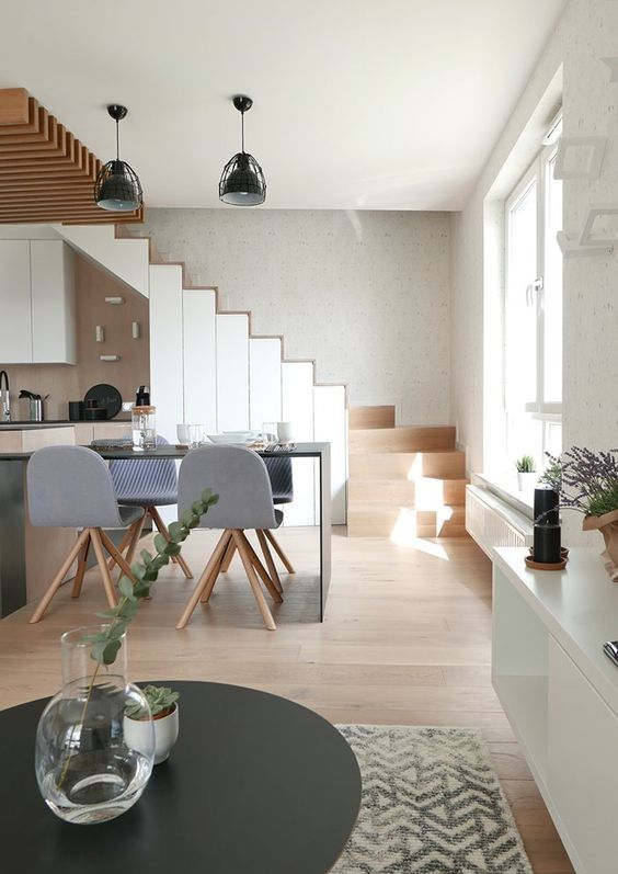 a Scandinavian kitchen built under the stairs and into the stairs, with stained and white cabinets, black fixtures