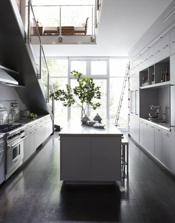 a Scandinavian kitchen with white cabinets, one part of it is placed under the stairs, with a large kitchen island and lots of natural light