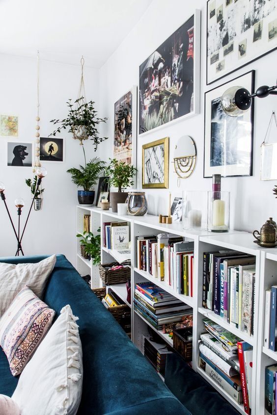 a Scandinavian living room with white crate bookshelves, a free form gallery wlal and potted plants plus lovely decor