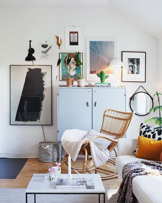 a Scandinavian space with a free form gallery wall, a rattan rocker chair, a sofa with printed pillows, a coffee table