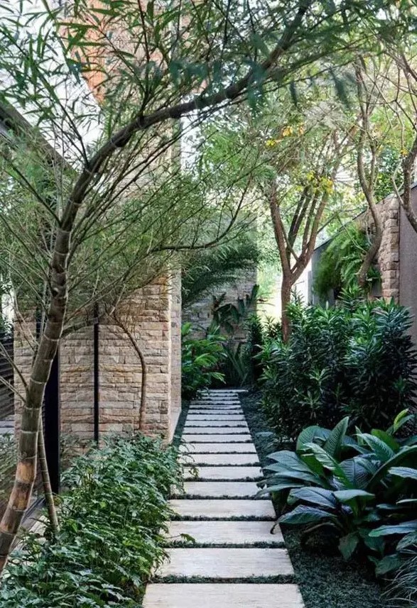 a beautiful and harmonious side yard with greenery, pavements, some trees is a peaceful and shadow-covered space